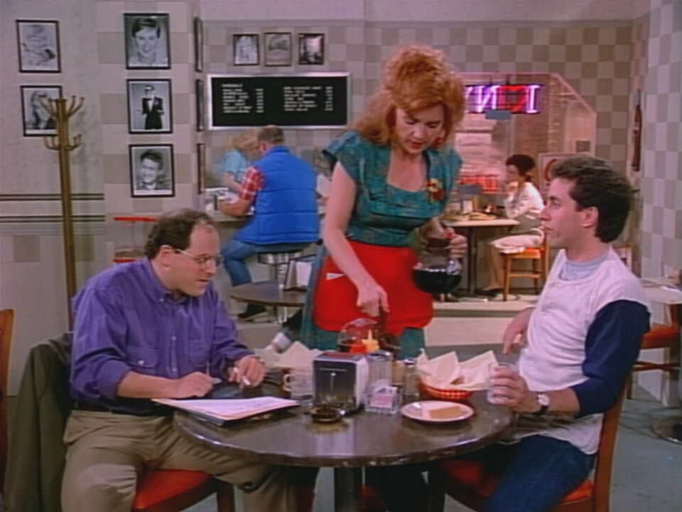 George and Jerry seated in the pilot's diner while Claire pours coffee between them.